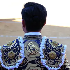 Detalle de la espalda de un torero con bordados dorados y azules, mostrando los vibrantes colores taurinos.