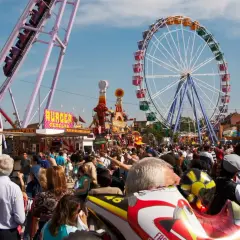 Feria en la Finca San Isidro Madrid con noria, atracciones y mucha gente disfrutando del día.