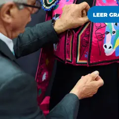 Un hombre ajusta un traje de luces rosa con caballos bordados, listo para una corrida en Madrid.