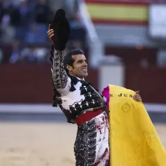 Un torero sonriente levanta su montera, con la muleta amarilla en la mano. Las caras de toreros son un reflejo de pasión y valentía.