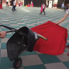 Jóvenes aprenden a torear con un capote y un toro de utilería.