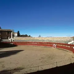 La plaza de toros de Las Ventas, la primera plaza de toros de España, con su ruedo de arena y gradas de piedra bajo un cielo azul.