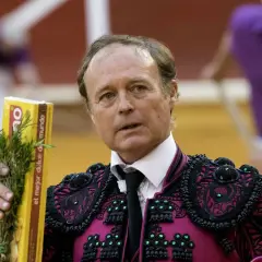 José Vázquez, torero con traje de luces, sostiene un ramo de romero y una caja amarilla.