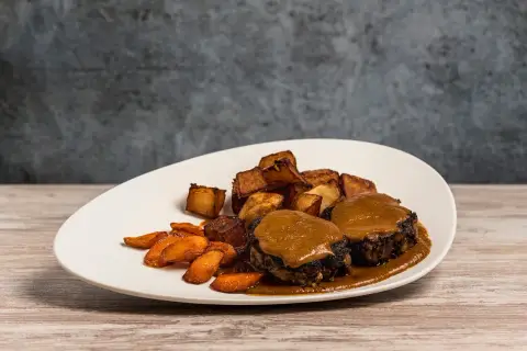 Plato de rabo de toro con patatas rústicas y zanahorias glaseadas. Una deliciosa receta para disfrutar.