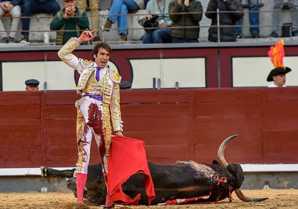 Un torero herido, con su traje manchado de sangre, se alza triunfante sobre un toro caído. La escena evoca la cruda realidad de la muerte torero.