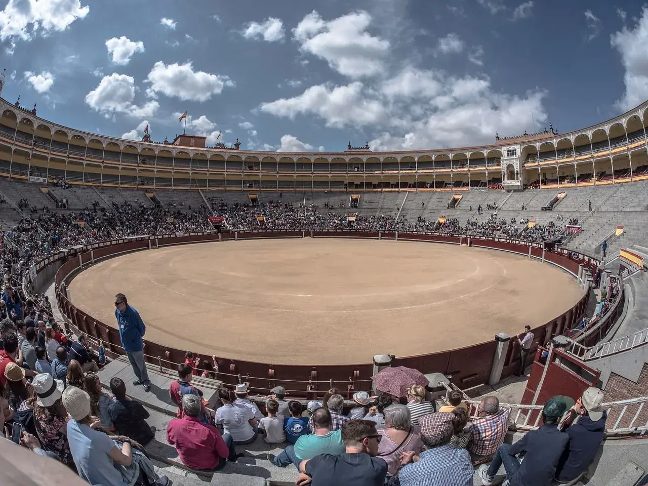 Espectadores en la plaza de toros, la plaza más grande de España, bajo un cielo azul con nubes.