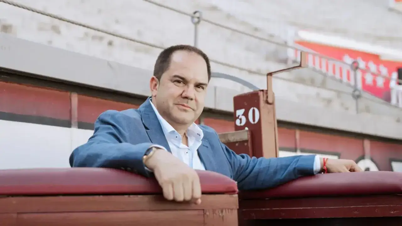 Sixto Naranjo, con traje azul, apoyado en asientos de cuero rojo en una plaza de toros.
