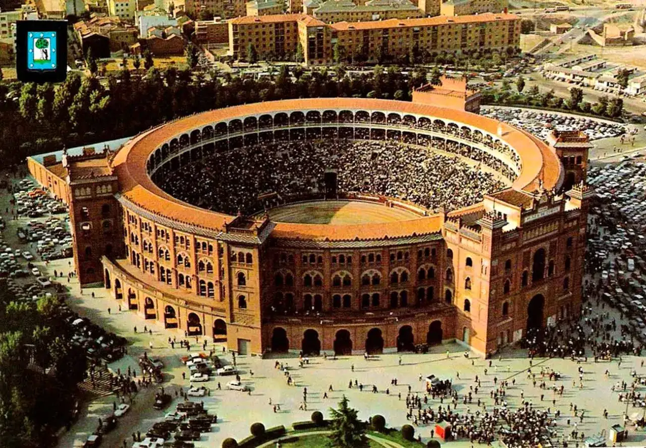 Vista aérea de una plaza de toros llena de público. El palco de las ventas, con su arquitectura detallada, se alza majestuoso.