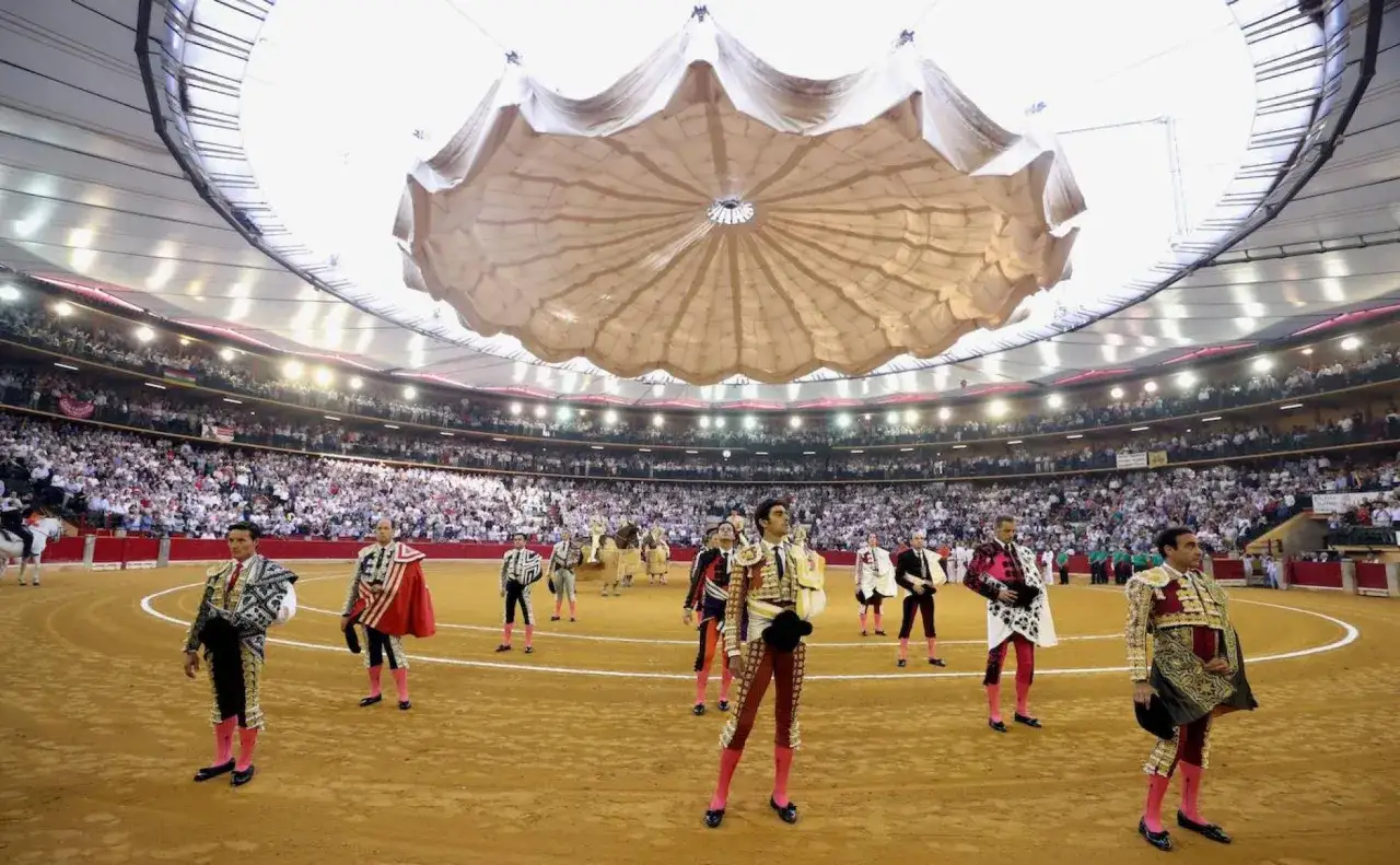 Toreros en traje de luces desfilan bajo la cubierta de una de las plazas de toros cubiertas en Espa&ntilde;a, ante un p&uacute;blico numeroso.