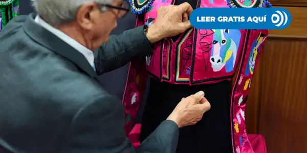 Un hombre ajusta un traje de luces rosa con caballos bordados, listo para una corrida en Madrid.